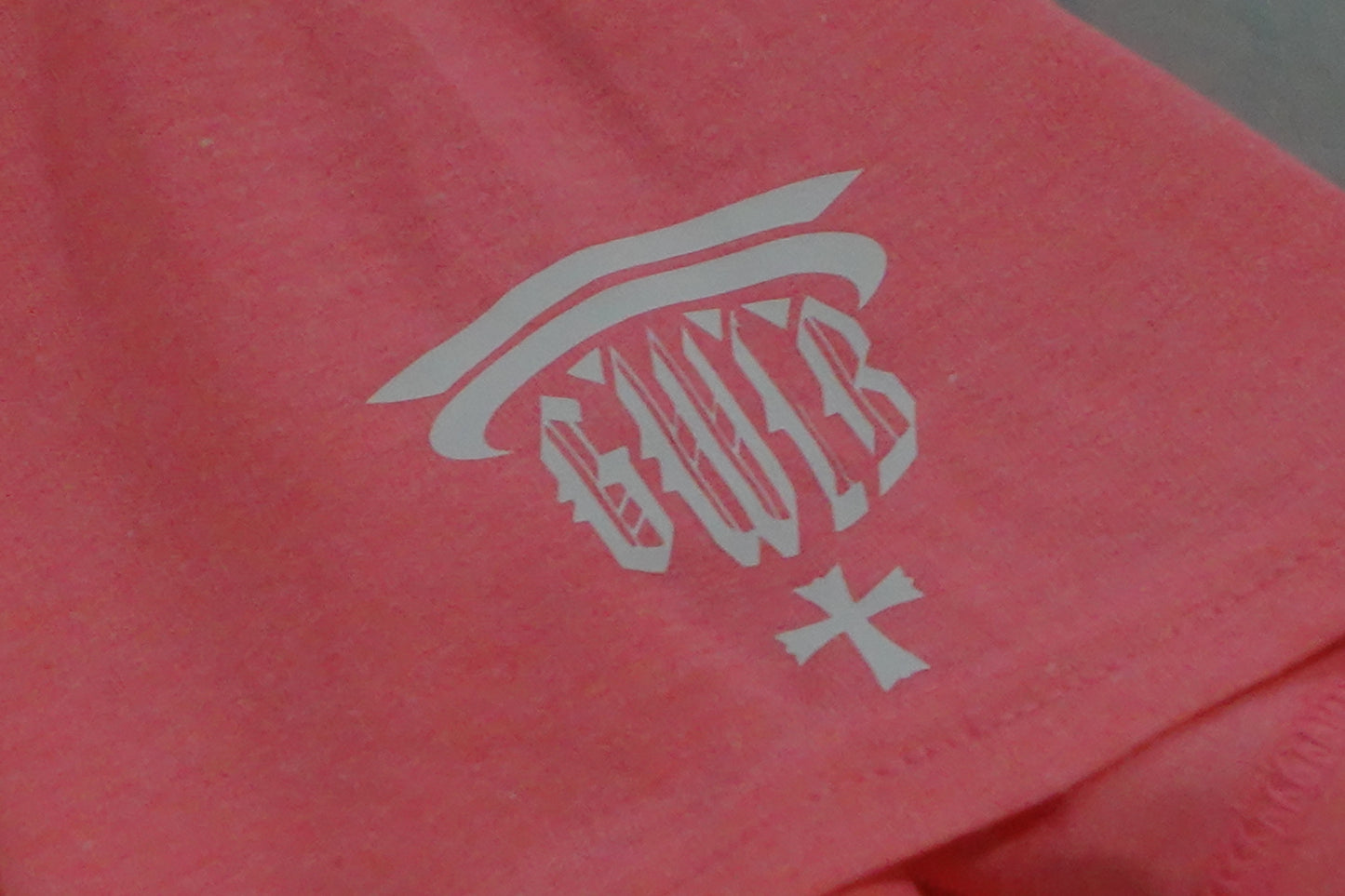 Close-up of a pink t-shirt with a white logo GWIB on the sleeve.