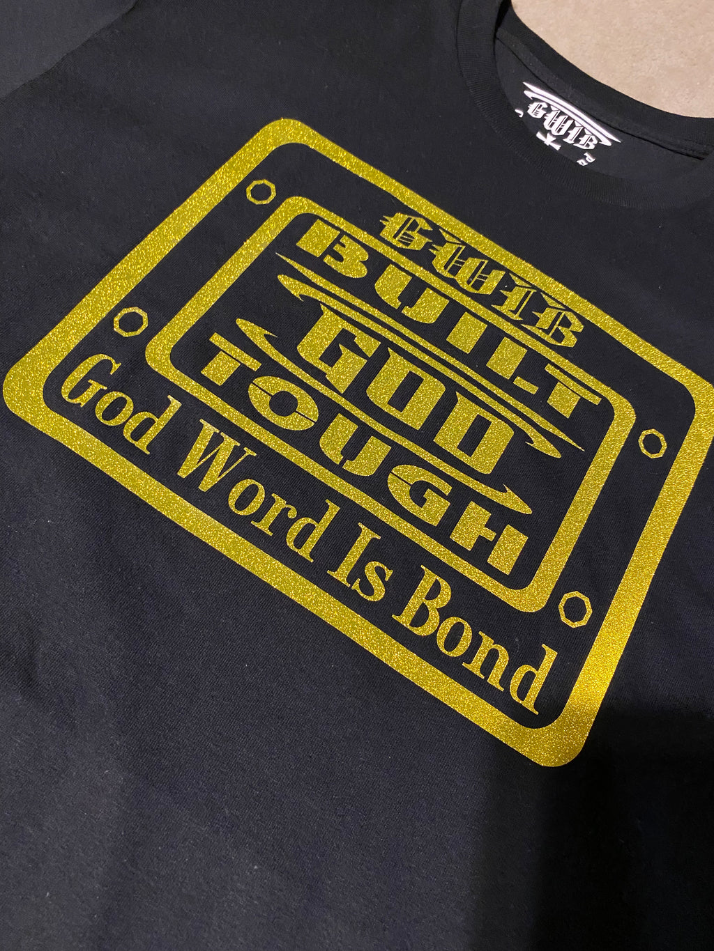 Built God Tough T shirt in black with a gold glitter design.